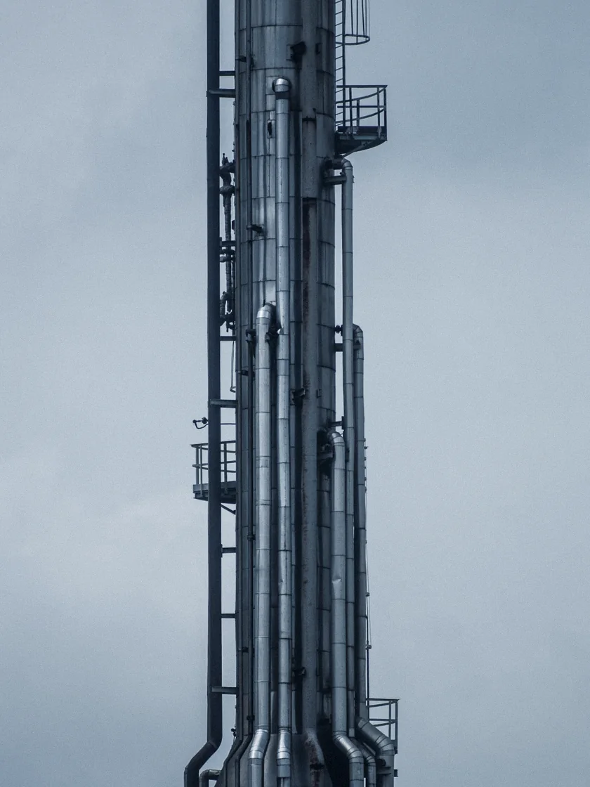 A steel process column against a pale sky
