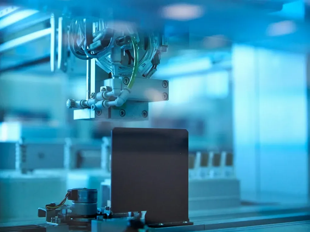 Robotic gripper running an experiment inside an automated, blue-lit lab cell